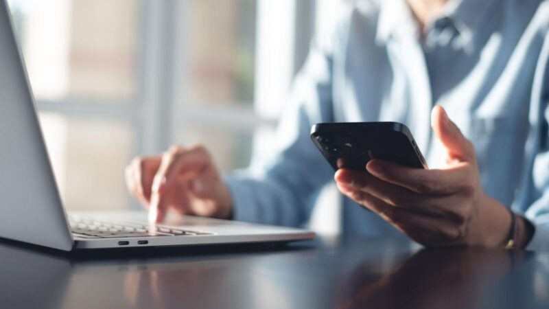A woman searching for your address on a laptop while holding smartphone