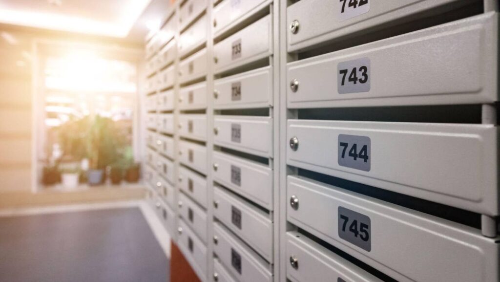 Someone looking at a row of white apartment mailboxes while trying to learn how to write apartment address.