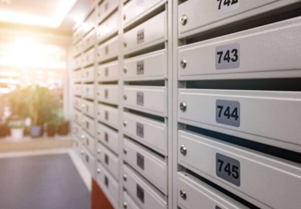 Someone looking at a row of white apartment mailboxes while trying to learn how to write apartment address.