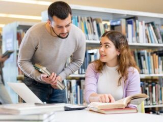 A woman in a library learning how to look up a lien on a property with help from someone else.