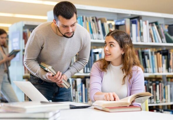 A woman in a library learning how to look up a lien on a property with help from someone else.