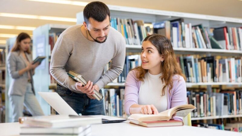 A woman in a library learning how to look up a lien on a property with help from someone else.